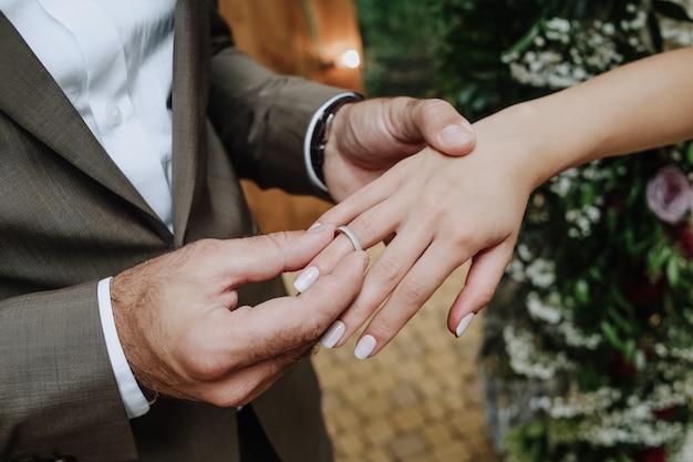 Bräutigam legt den Ring auf die Hand der Braut bei der Zeremonie