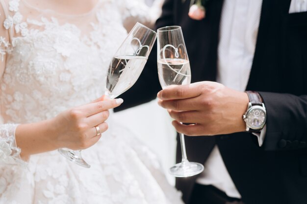 Bräutigam mit Braut klopfen Gläser mit Champagner an