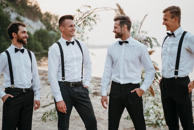 Kostenloses Foto bräutigam und beste männer posieren am strand