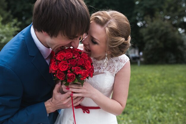 Bräutigam und Braut Beißen die Hochzeit Bouquet