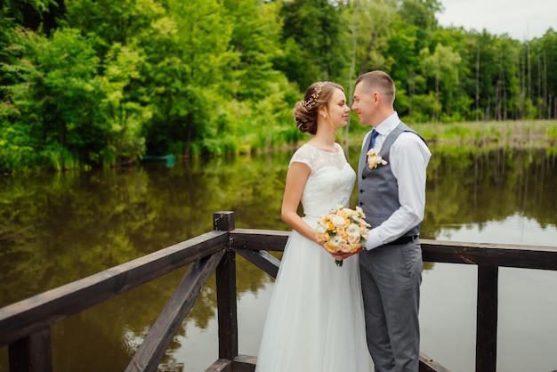 Bräutigam und Braut im Hochzeitskleid gainst eine hölzerne Veranda auf dem See.