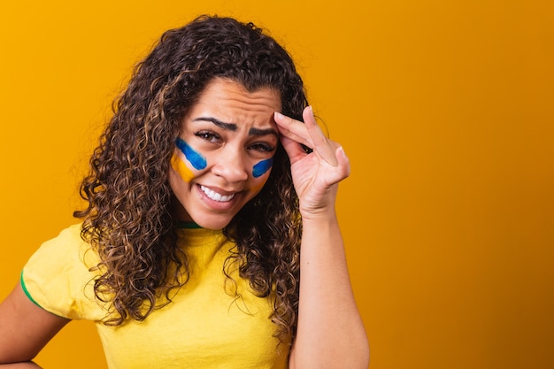 Brasilianischer fan enttäuscht auf gelbem grund mit brasilianischer bluse