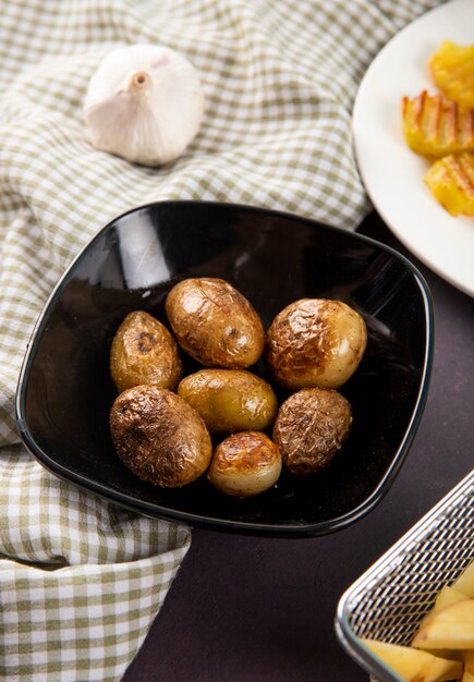 Bratkartoffeln der Seitenansicht mit Knoblauch auf dunkelgrauem Hintergrund