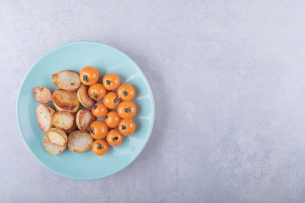 Bratkartoffeln und Kirschtomaten auf blauem Teller.