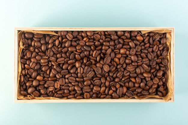 Braune Kaffeesamen einer Draufsicht innerhalb der Schachtel auf der blauen Wandkaffeetasse-Fotosamen trinken