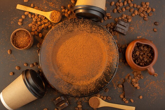 Braune Kaffeesamen von oben mit schwarzen Kaffeetassen mit Schokoriegeln