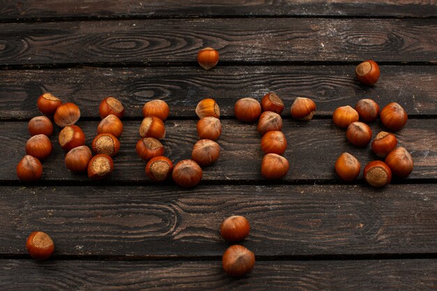 Braune Nüsse ganze leckere Nüsse Wort geformt auf einem braunen rustikalen Holztisch