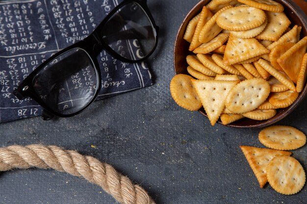 Braune Platte der Draufsicht mit Crackern und Seilen auf dem Foto-Snack des knusprigen Crackers des grauen Hintergrunds