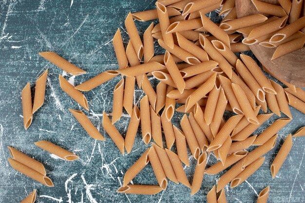 Braune rohe Penne-Nudeln auf blauem Hintergrund. Hochwertiges Foto