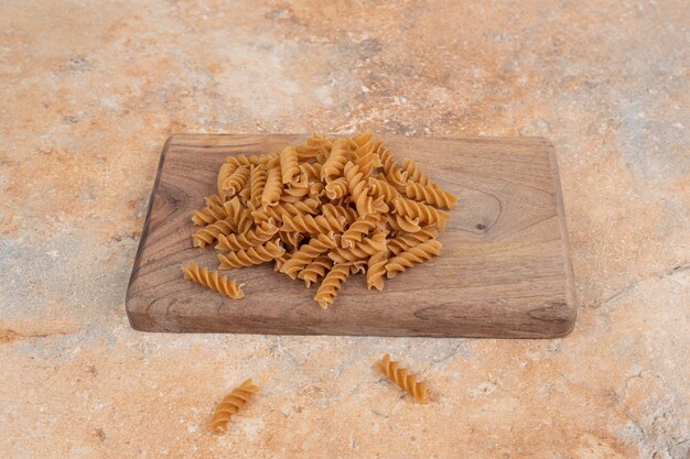 Braune ungekochte Spiralmakkaroni auf Holzbrett. Hochwertiges Foto