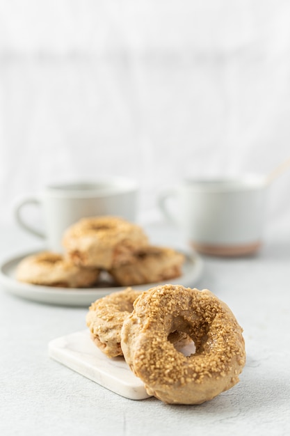 Brauner Donut neben weißem Keramikbecher auf weißem Tisch