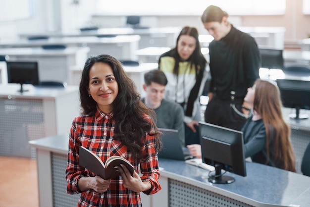 Braunes Buch in Händen. Gruppe junger Leute in Freizeitkleidung, die im modernen Büro arbeiten