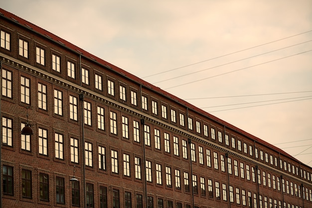 Braunes großes modernes Gebäude mit Fenstern unter einem bewölkten Himmel während des Sonnenuntergangs