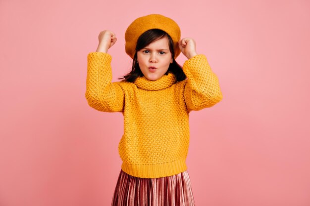 Braunhaariges Kind winkt mit Fäusten Studioaufnahme eines emotionalen Kindes in gelber Kleidung