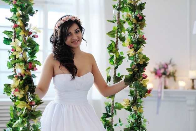 Braut auf einer Schaukel mit Blumen