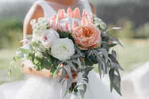 Kostenloses Foto braut hält den schönen brautblumenstrauß mit rosen, eukalyptus und riesigem protea