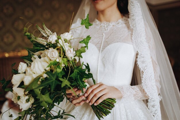 Braut hält Hochzeitsblumenstrauß von weißen Blumen in ihrer Hand