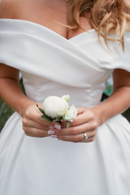 Braut hält in ihren Armen kleine weiße Boutonniere