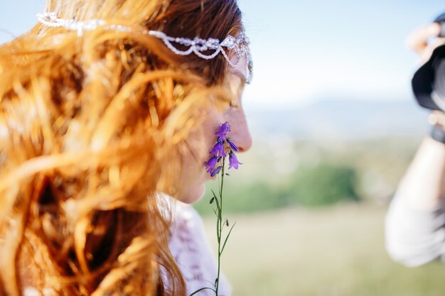 Braut mit dem goldenen roten Haar lehnt eine kleine violette Blume