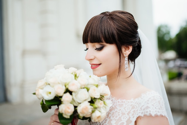 Braut mit einem Blumenstrauß, lächelnd. Hochzeitsporträt der schönen Braut. Hochzeit. Hochzeitstag.