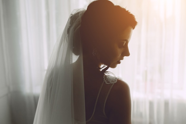 Braut posiert in einem großen Fenster auf der Kamera