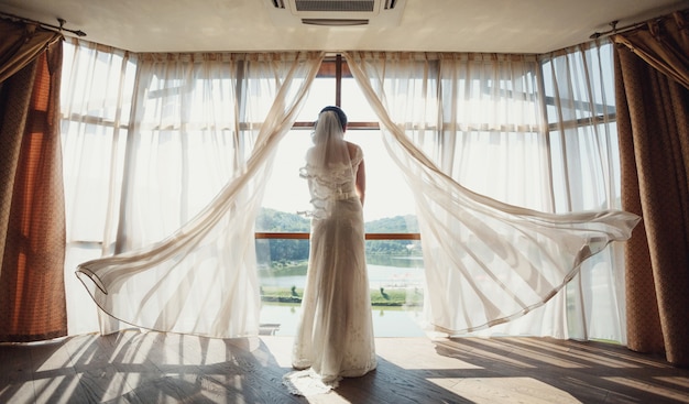Braut steht vor einem Panoramafenster
