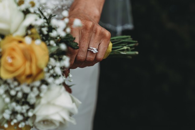 Braut trägt einen Ehering, der ihren Blumenstrauß hält