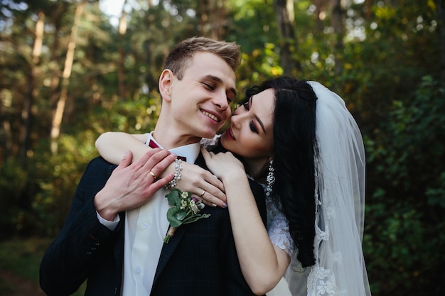 Braut umarmt lächelnde Verlobung stehend im Wald