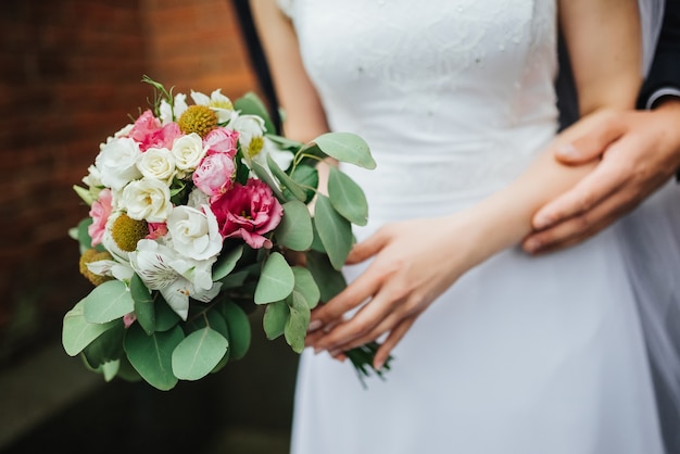 Braut und Bräutigam am Hochzeitstag, der draußen nahe Architektur geht.