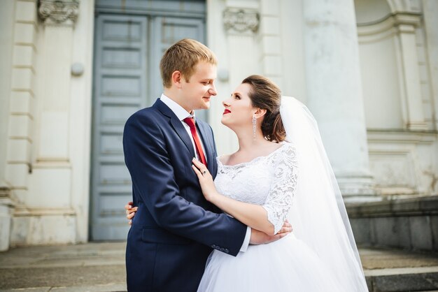 Braut und Bräutigam am Hochzeitstag, der draußen nahe Architektur geht.