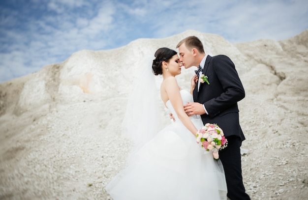 Braut und Bräutigam am Hochzeitstag draußen gehend nahe dem Berg des vulkanischen Sandes.