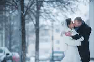 Kostenloses Foto braut und bräutigam gehen auf der europäischen stadt im schnee
