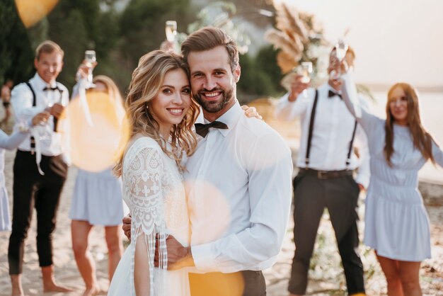 Braut und Bräutigam haben ihre Hochzeit mit Gästen am Strand