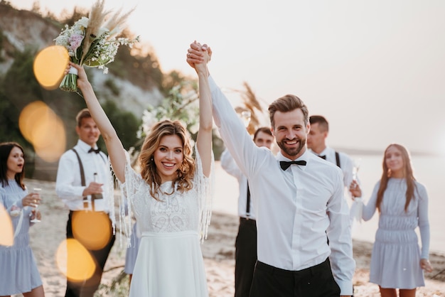 Braut und Bräutigam haben ihre Hochzeit mit Gästen am Strand