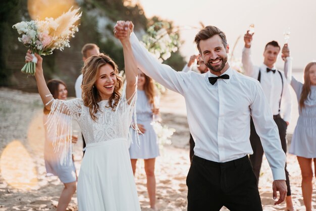 Braut und Bräutigam haben ihre Hochzeit mit Gästen am Strand