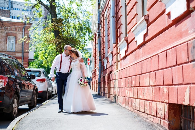 Braut und bräutigam in brautkleidern, die an einem hochzeitstag durch die straßen der stadt gehen