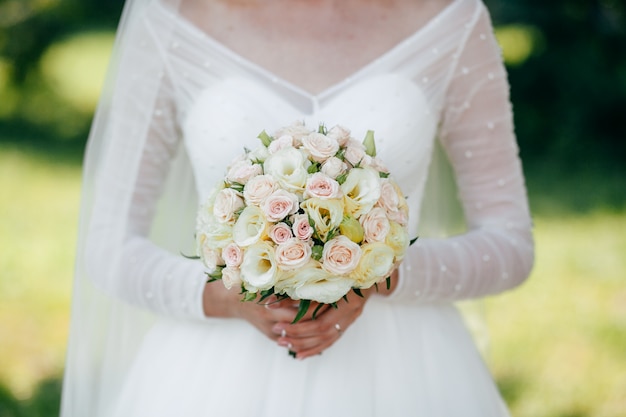 Braut und Bräutigam mit einem Strauß roter Blumen und Grüns in der Hand