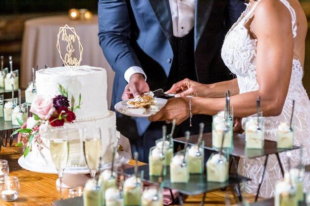 Braut und Bräutigam schneiden die schöne weiße Hochzeitstorte