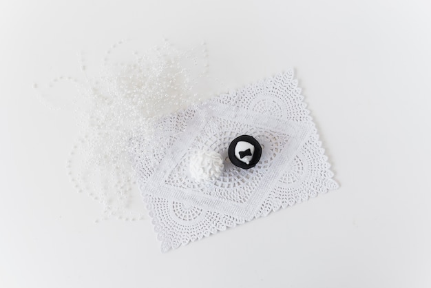 Kostenloses Foto braut- und bräutigamschalenkuchen auf doily nahe perlen auf weißer oberfläche