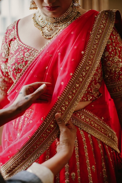 Kostenloses Foto brautjungfer hilft, das traditionelle indische brautkleid zu tragen