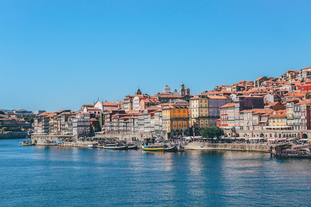 Breiter Schuss von Booten auf dem Gewässer nahe Häusern und Gebäuden in Porto, Portugal