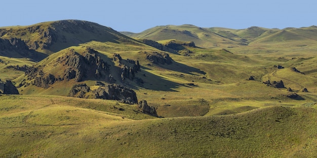 Breiter Schuss von leeren grasbewachsenen Hügeln mit einem blauen Himmel im Hintergrund zur Tageszeit