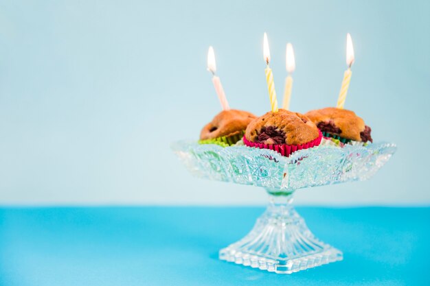 Brennende Kerzen über dem kleinen Kuchen auf blauem Hintergrund