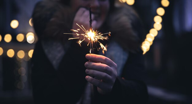 Brennende Wunderkerzen in den Händen einer jungen Frau im Dunkeln