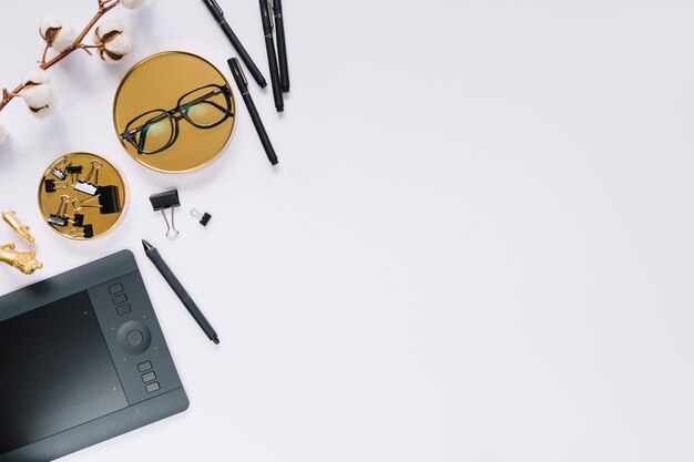 Brille; Stift; Papierklammer; grafischer digitaler Tablette- und Baumwollzweig auf Hintergrund