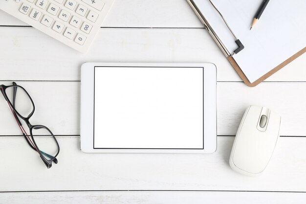 Brille, Taschenrechner und Tablette auf weissem Schreibtisch