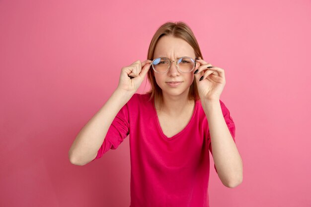 Brille tragen. Kaukasisches Porträt der jungen Frau lokalisiert auf rosa Wand, Monochrom. Schönes weibliches Modell.