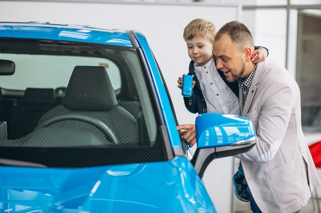 Bringen Sie mit dem Sohn hervor, der ein Auto in einem Autosalon betrachtet