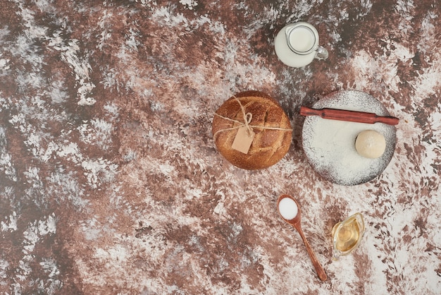 Brötchen auf Marmor mit Teig und Zutaten.