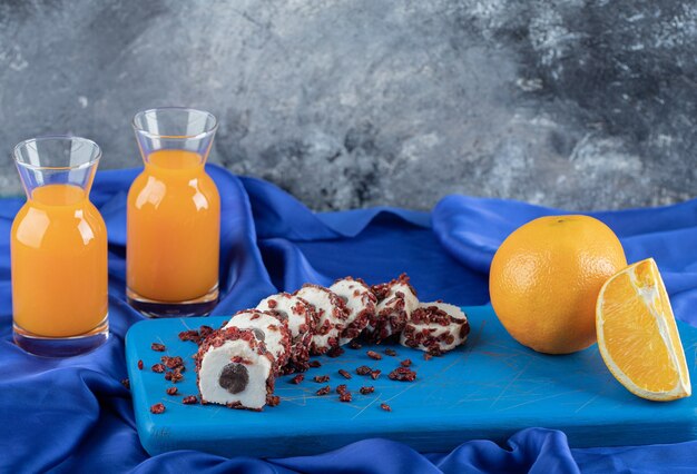 Brötchen mit Hagebutten auf blauem Brett mit Orangensaft.